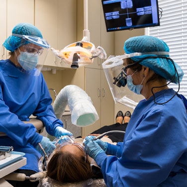 Dr. Nancy Shiba and her assistant operating on a dental patient at Nancy Shiba, DDS in San Jose.